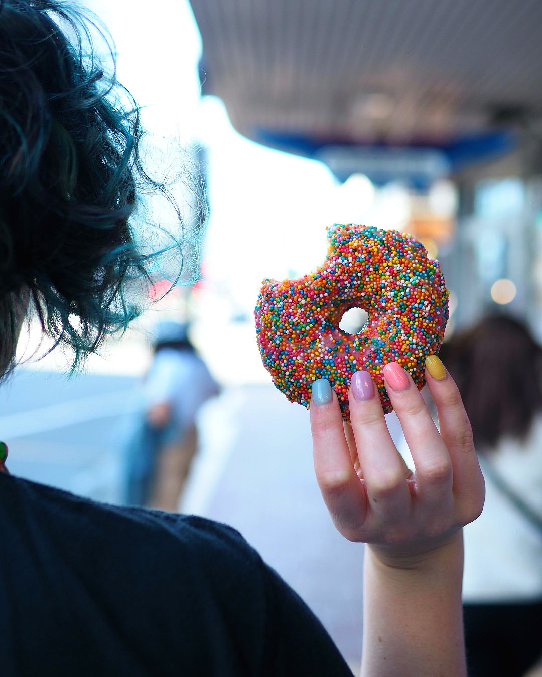 Someone holds up a delicious looking doughnut from Sixes and Sevens Deli, one of the best places for breakfast in Wellington.