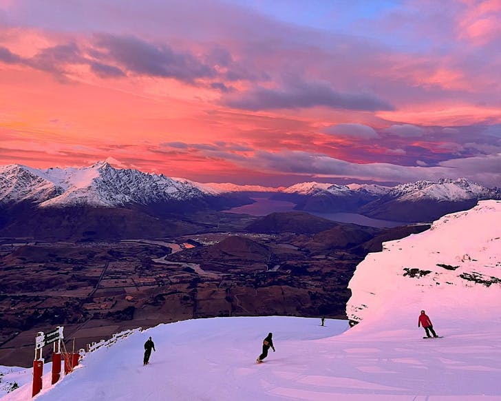 People skiing under a purple sunset