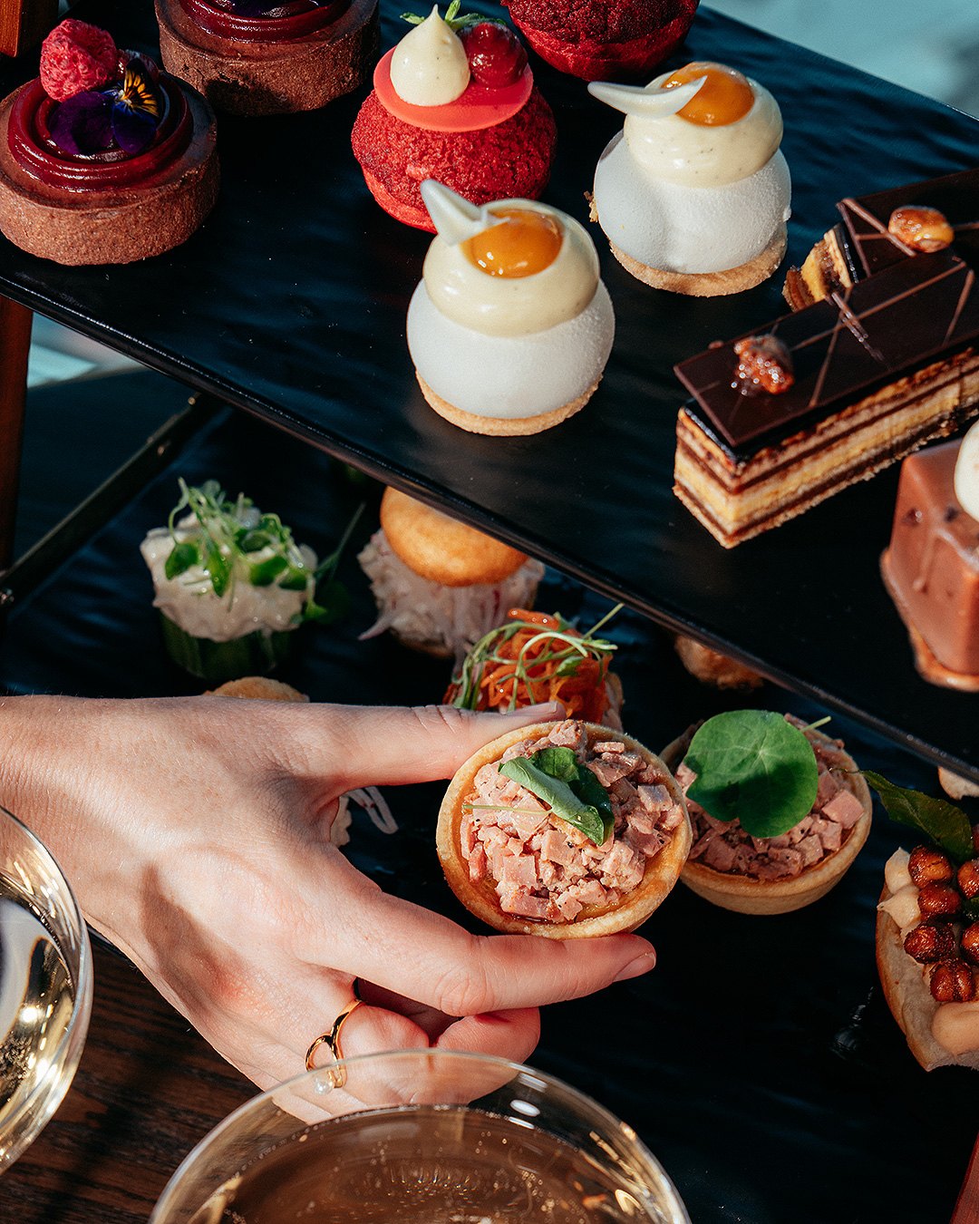 Someone helps themselves to a fancy at Sky Tea at SkyBar, one of the best afternoon teas in Auckland.
