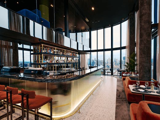 A large bar in the centre of a room with a large window overlooking the city.