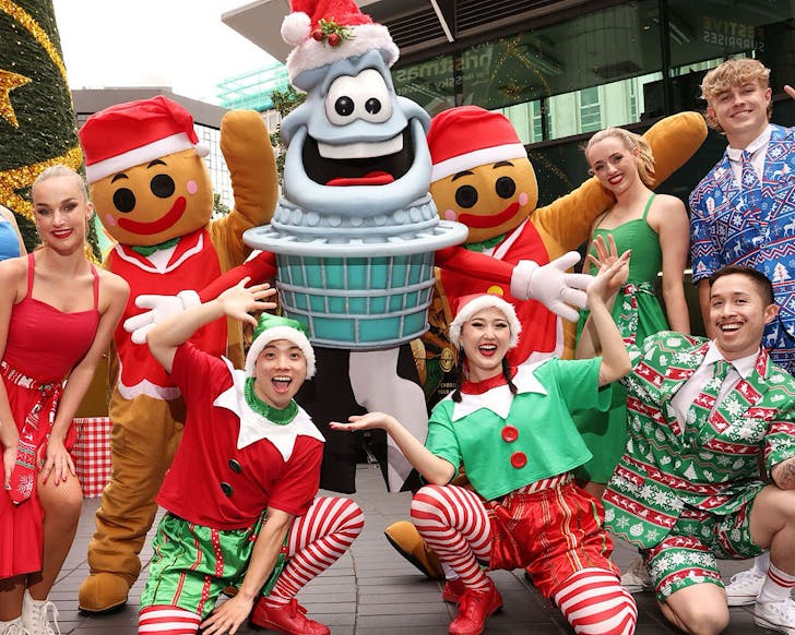 A group of people in Christmas dress-up, and a Sky Tower, pose for the camera.