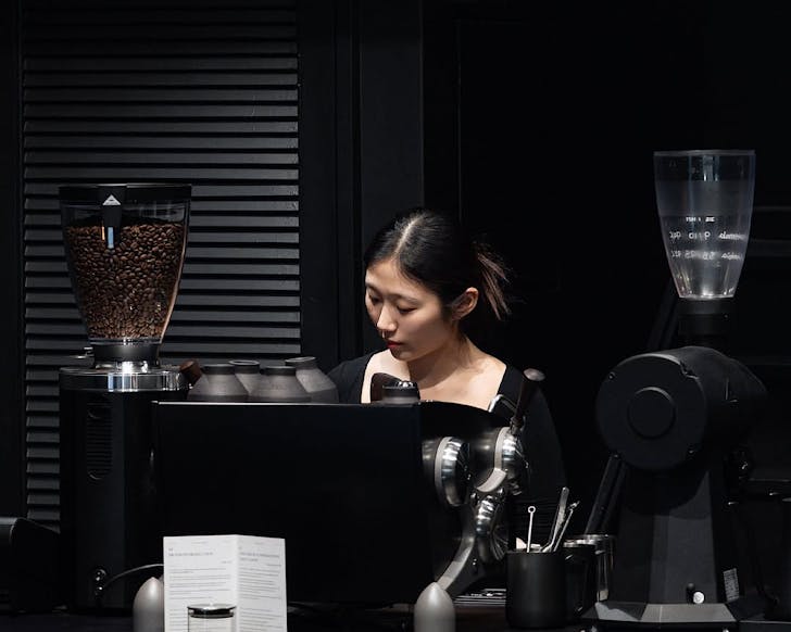 A barista makes coffee in chic, black surrounds. 