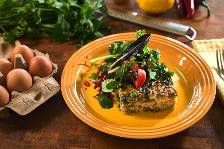 A slice of the frittata on a plate alongside the roasted sweet potatoes