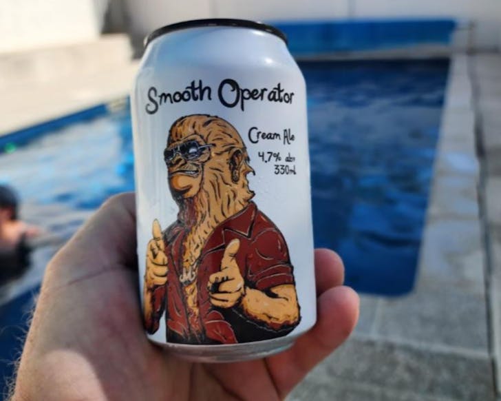 Someone holds a white can of craft beer with a wookie wearing a red shirt on it. 