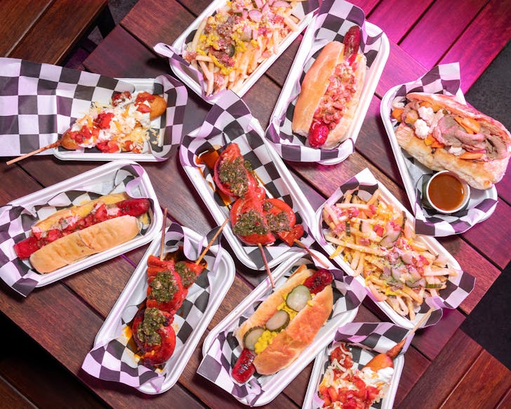 a table full of hot dogs and dishes featuring sausages