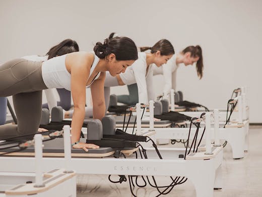 A group of people do pilates on reformer machines at So Fitness. 