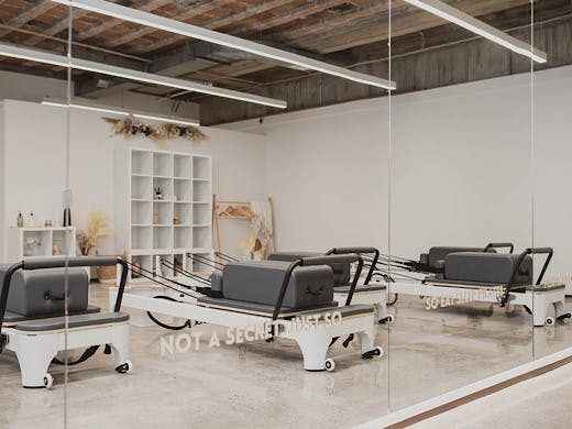 A bunch of reformer pilates machines reflected in a mirror at So Fitness’ new digs. 