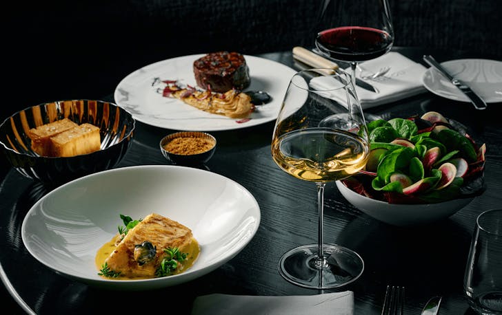 A table set with different dishes including steak and sugar loaf. 