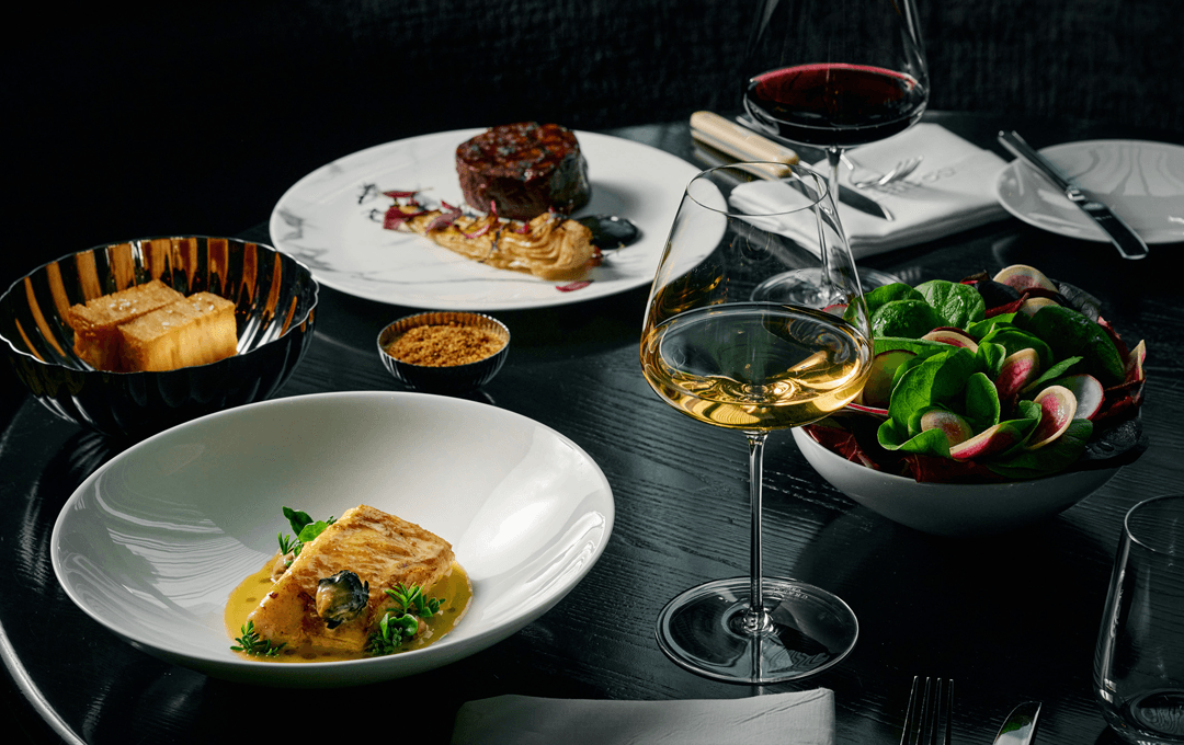 A table set with different dishes including steak and sugar loaf. 