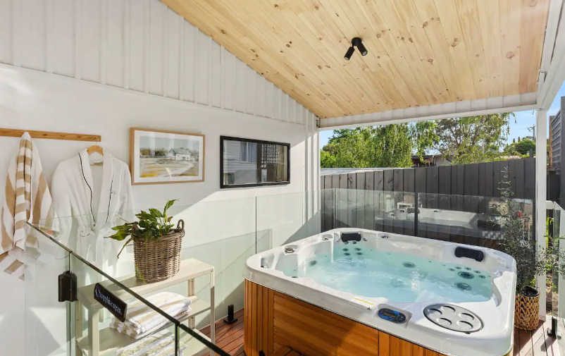 A large spa under a roof with a view of the garden at the best outdoor spa Airbnb Victoria.