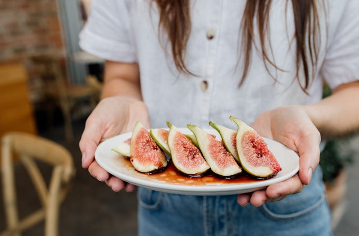 someone holding a plate of cut up figs