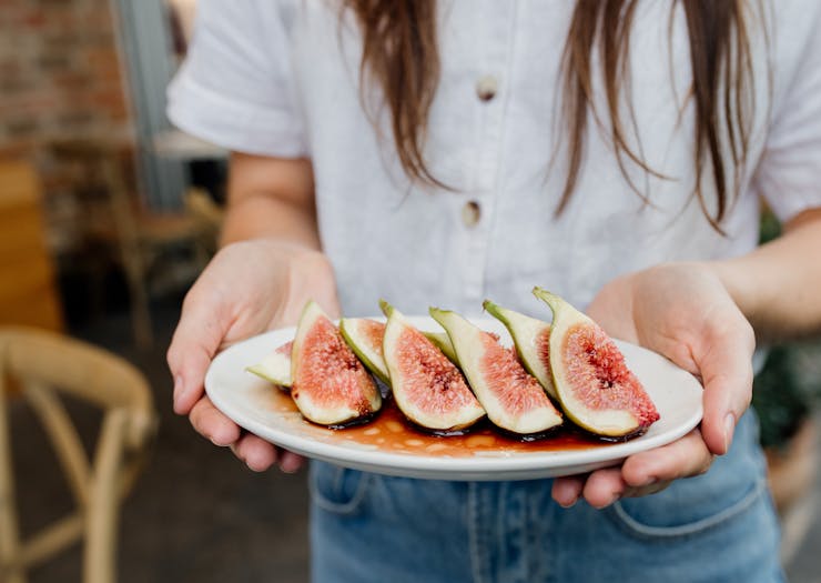 someone holding a plate of cut up figs