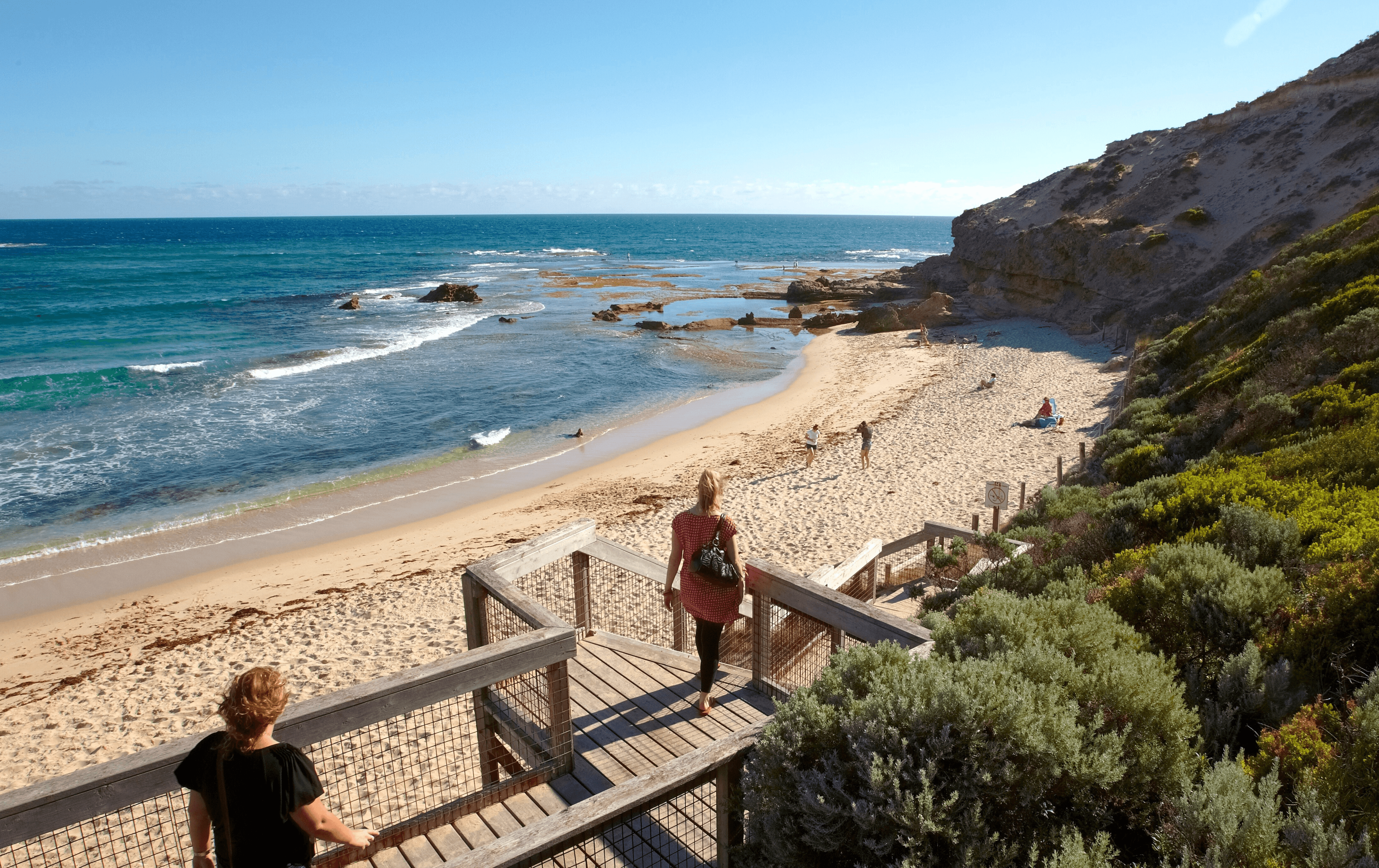 People walking down a wooden staircase to one of the best beaches in Victoria.