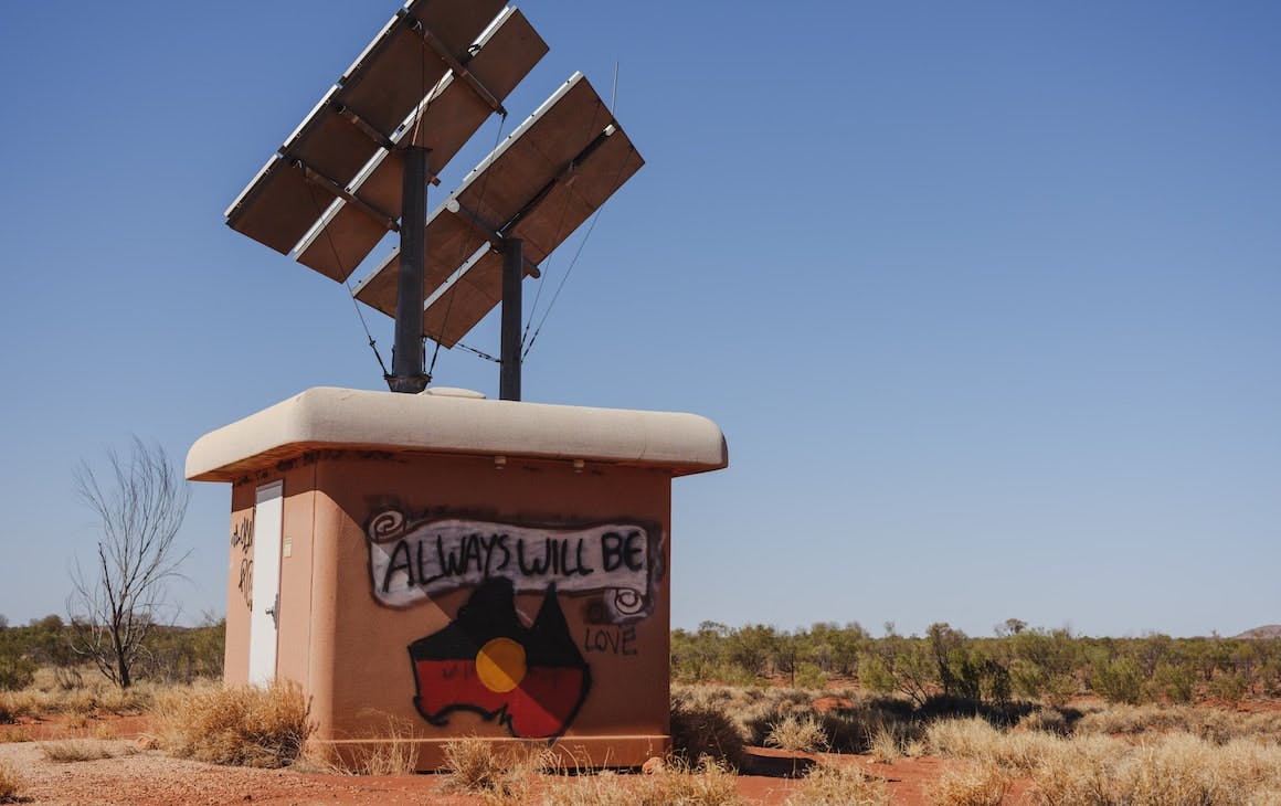 An outhouse with graffiti reading 