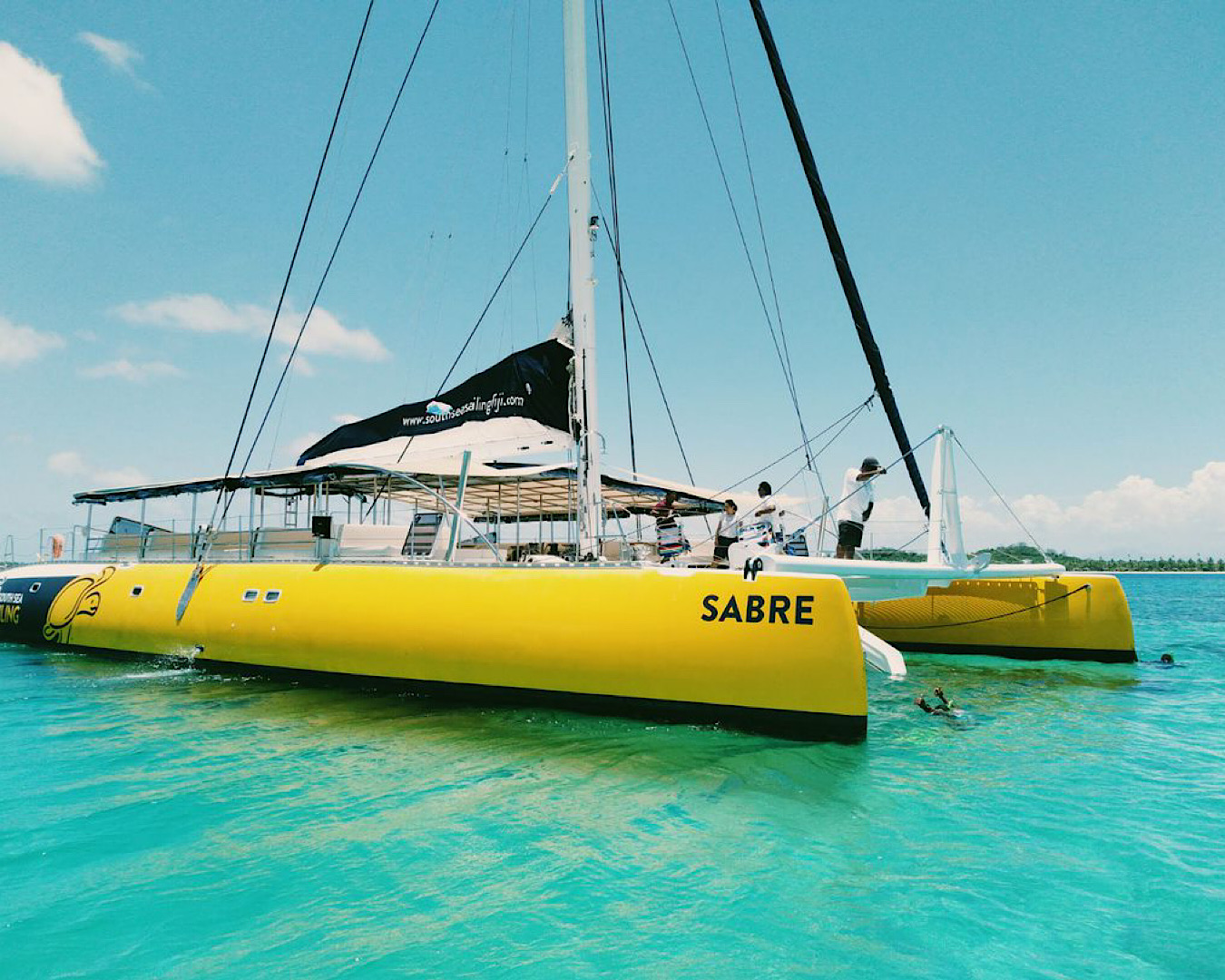 Massive yellow catamaran cruising on turquoise Fijian waters. 