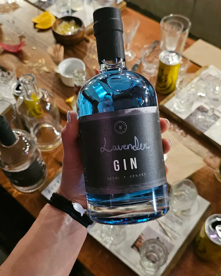 Alice holds a bottle of blue gin she made herself.