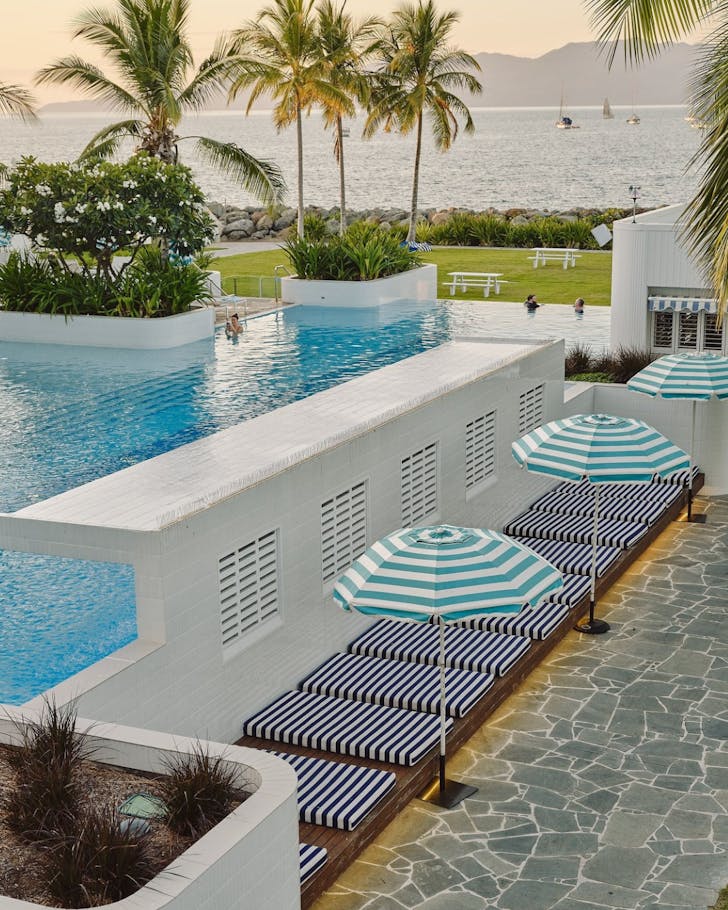 A view of blue umbrellas, an infinity pool looking out to the Coral Sea and palm trees at Splash Bar in Townsville. 