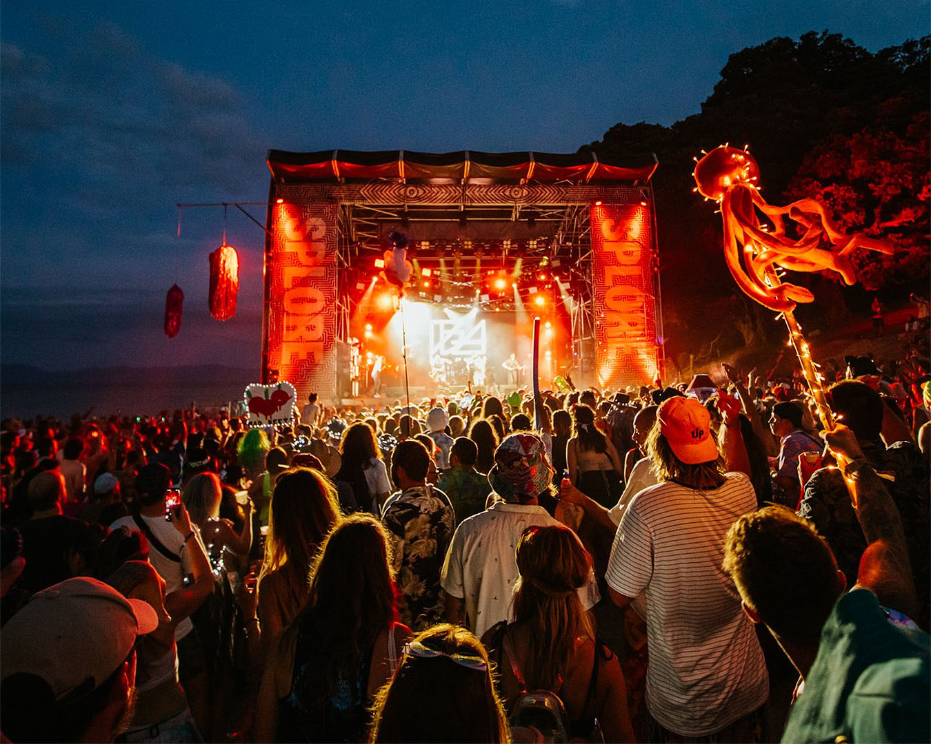 People watch an act on stage amongst multicoloured lights at Splore, one of the best festivals in NZ.