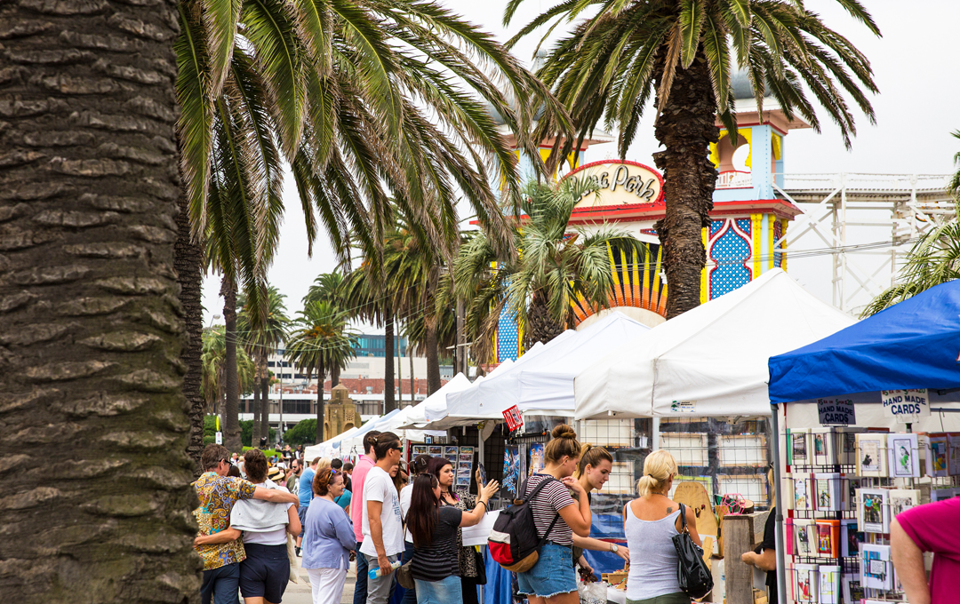 A street with people and palm trees, one of the best markets in Melbourne and Victoria.