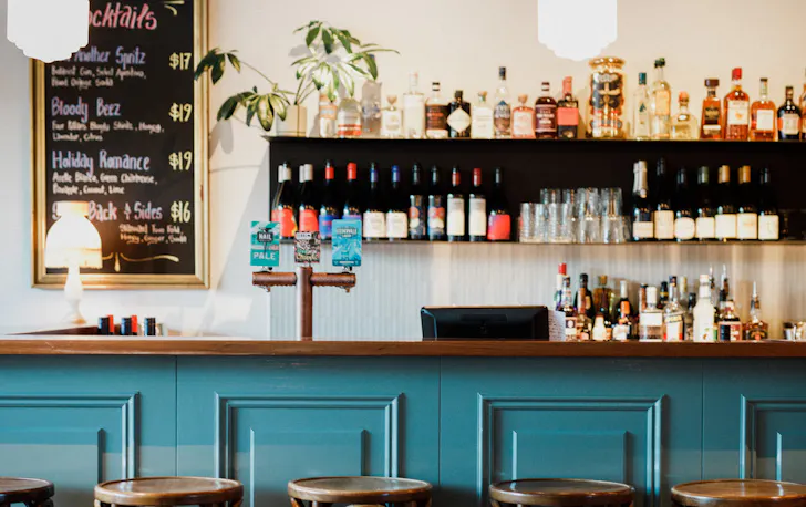 a green bar with a shelf of drinks behind it