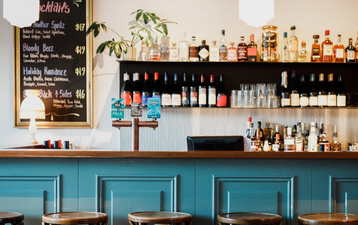 a green bar with a shelf of drinks behind it
