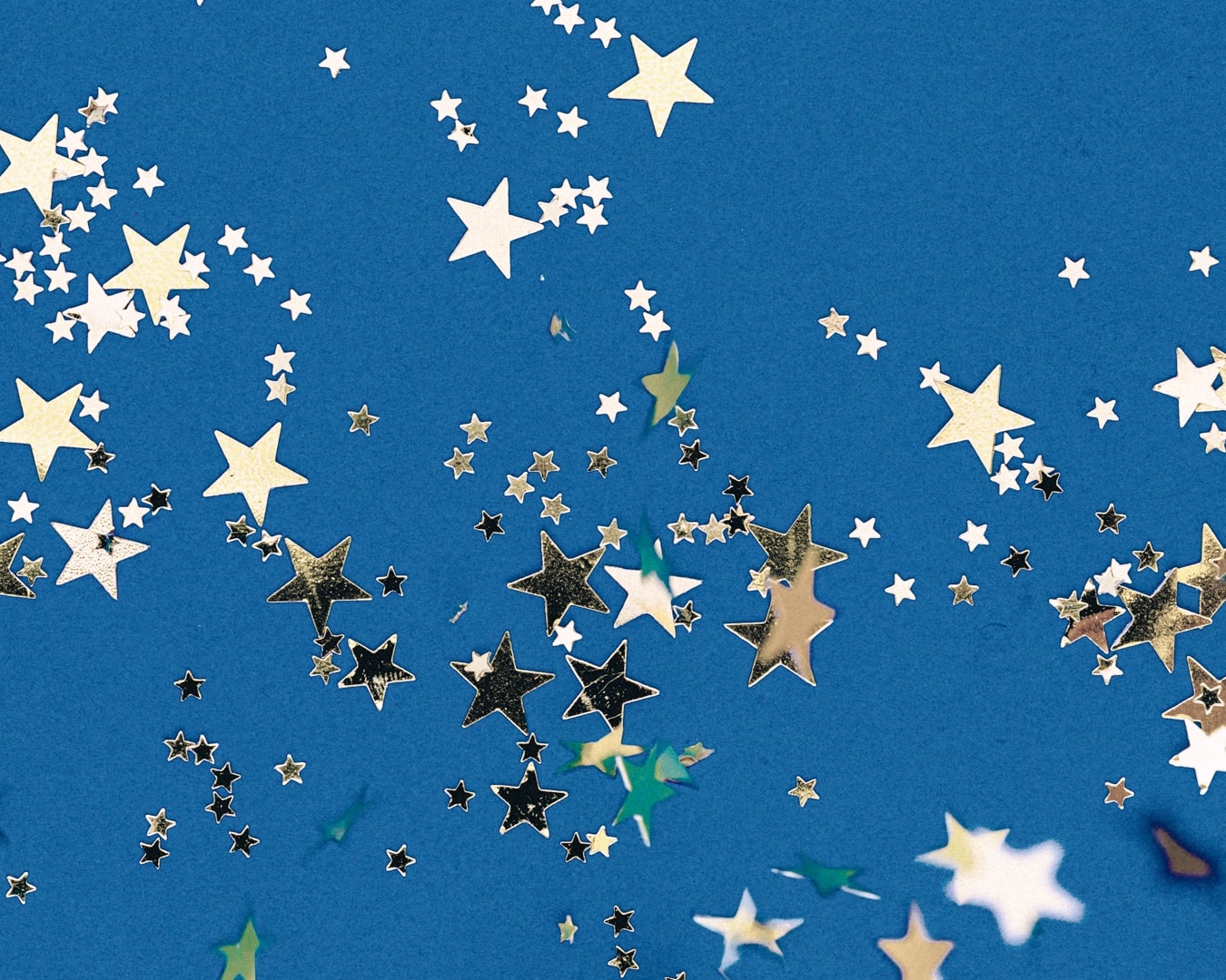 Star shaped confetti in assorted sizes on a blue background to look like the night sky. 