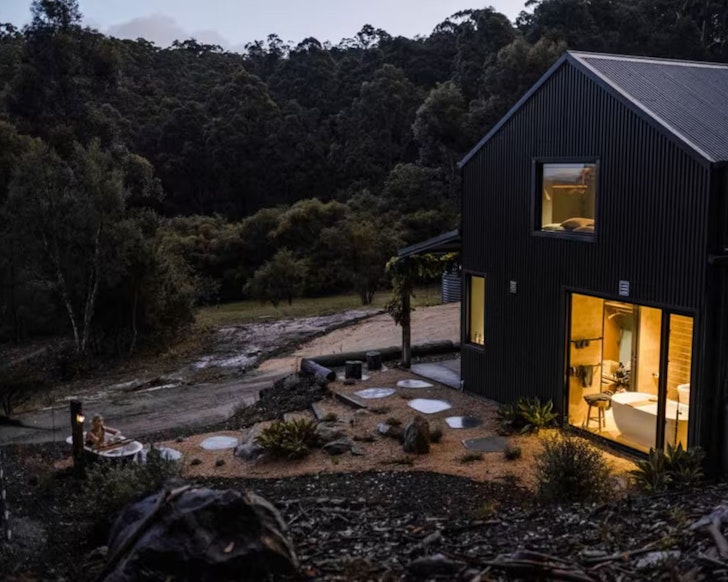 A woman lies in the outdoor bath outside Stillwood Retreat one of the best romantic getaways in Australia
