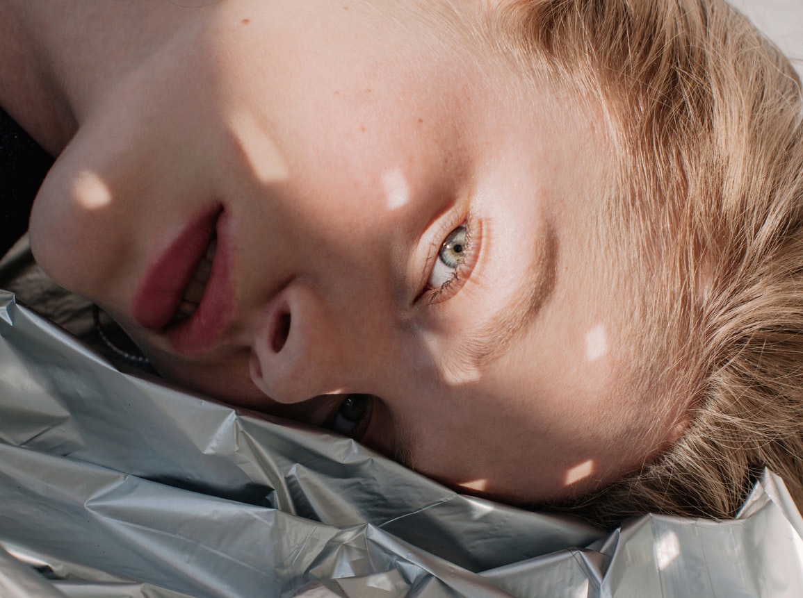 A woman lies on a sheet of plastic. 