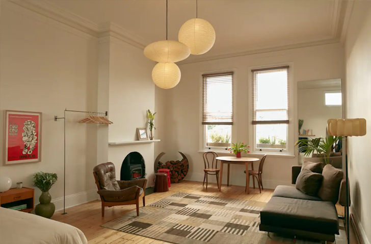 Three circle chandeliers emit a warm light into this Airbnb Melbourne living room, boasting art deco interiors.