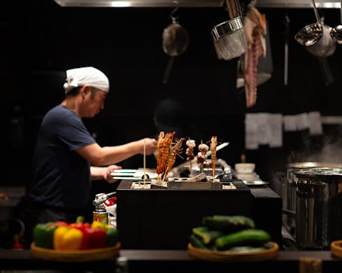 Chef grills skewers.