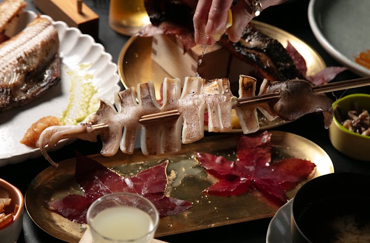 Vicki squeezes a lemon wedge over a skewer of squid. 