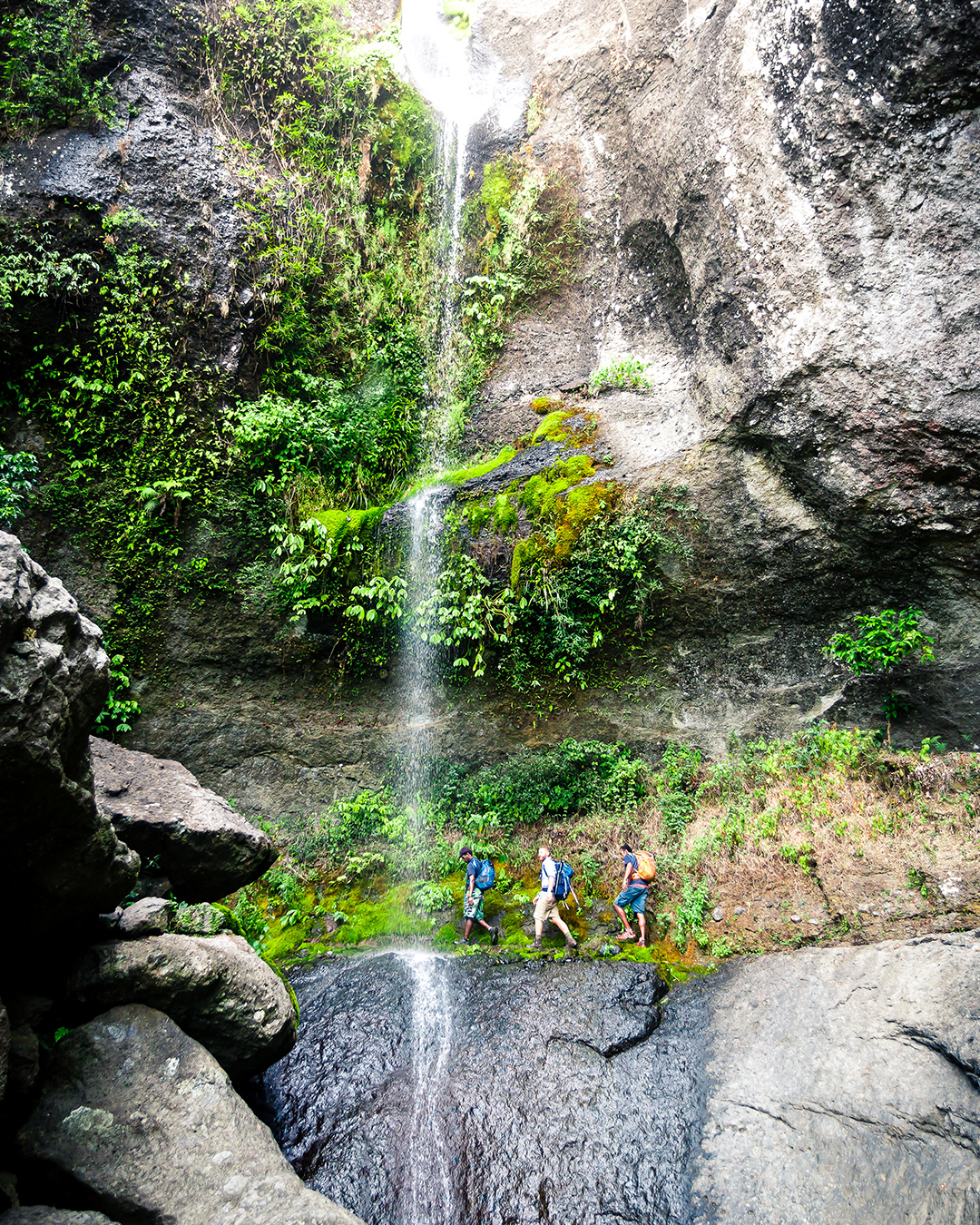A group trekking past a waterfall in Koroyanitu National Park