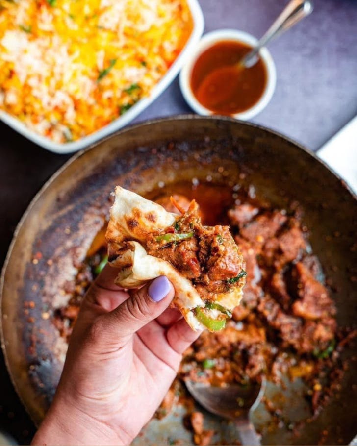 A person tucks into the saucy chicken jalfrezi from Suncourt Indian. 