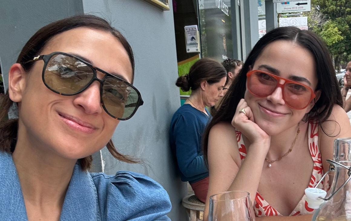 Two women wearing sunglasses and smiling 