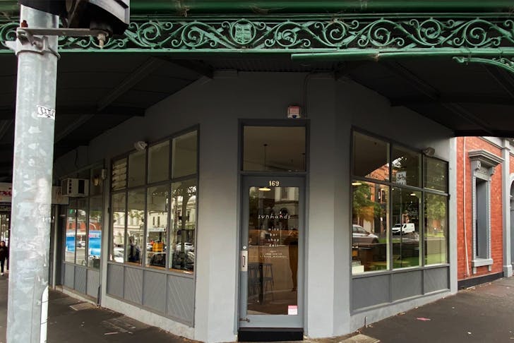 A shopfront with a green iron roof awning. 