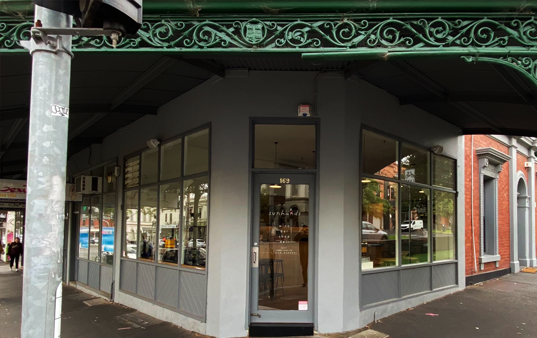 A shopfront with a green iron roof awning. 