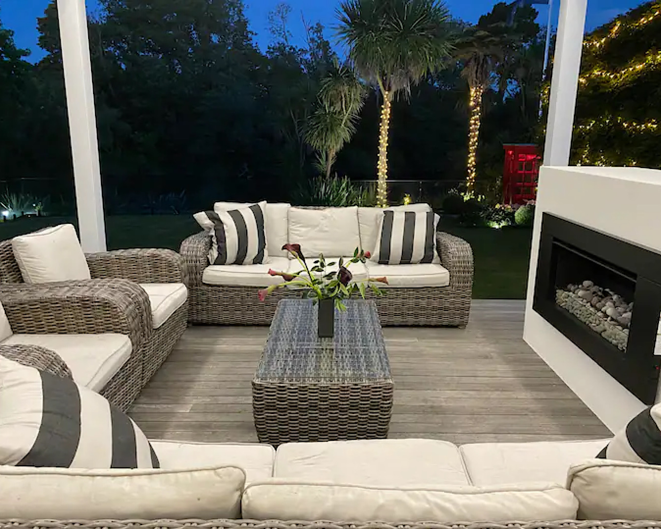 Large comfy chairs make a cosy setting around an outdoor fireplace at this Sunny Hamilton Home On The River Hamilton airbnb. 