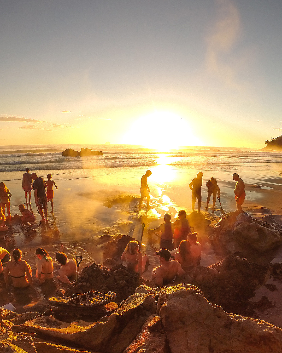 People enjoy Hot Water Beach at sunrise.