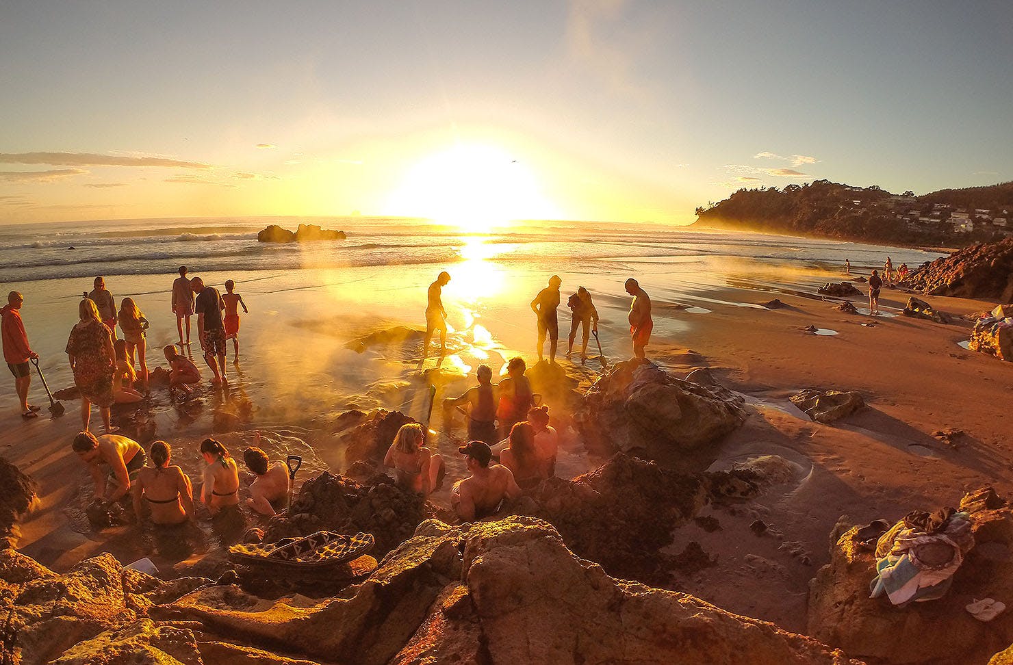 People enjoy the hot pools at Hot Water Beach at sunrise.