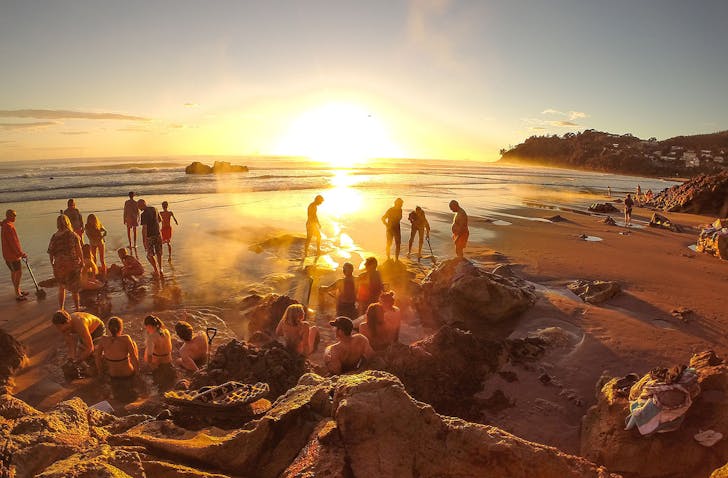 People enjoy the hot pools at Hot Water Beach at sunrise.