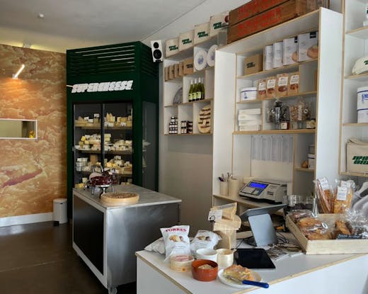 The inside of a cheese store with various cheeses and products.