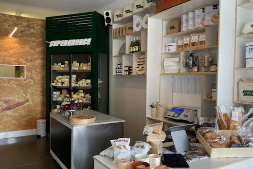 The inside of a cheese store with various cheeses and products.