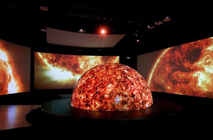 The Neighbourhood Earth exhibition featuring an illuminated globe with surrounding screens.