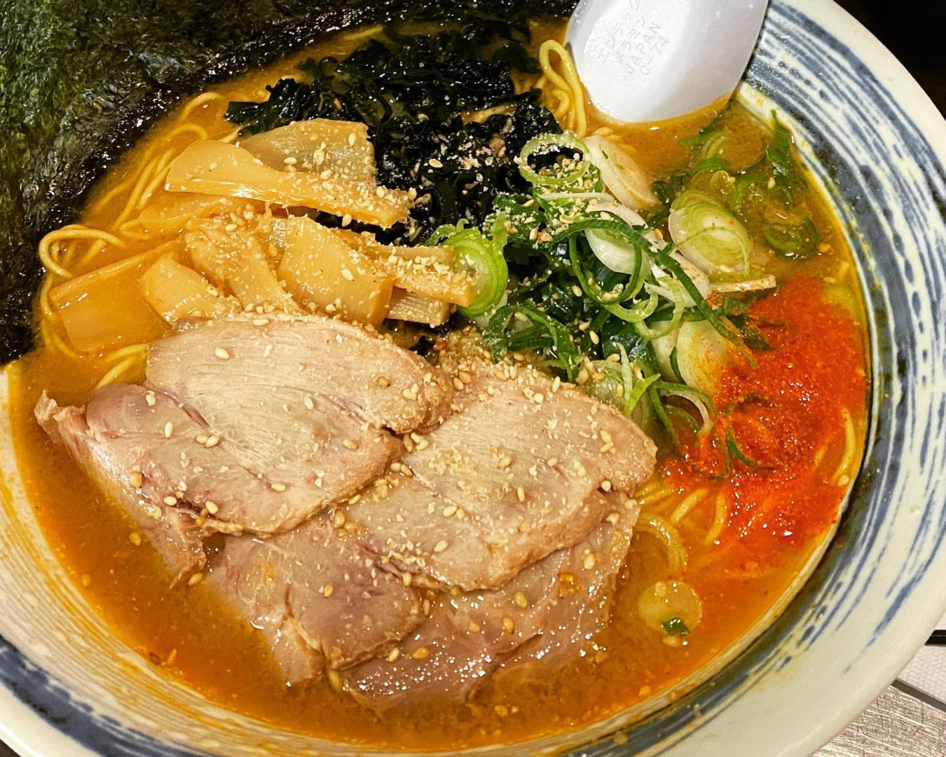 A glorious bowl of TANPOPO ramen featuring slices of pork, spring onion, noodles and more in a fragrant broth. 