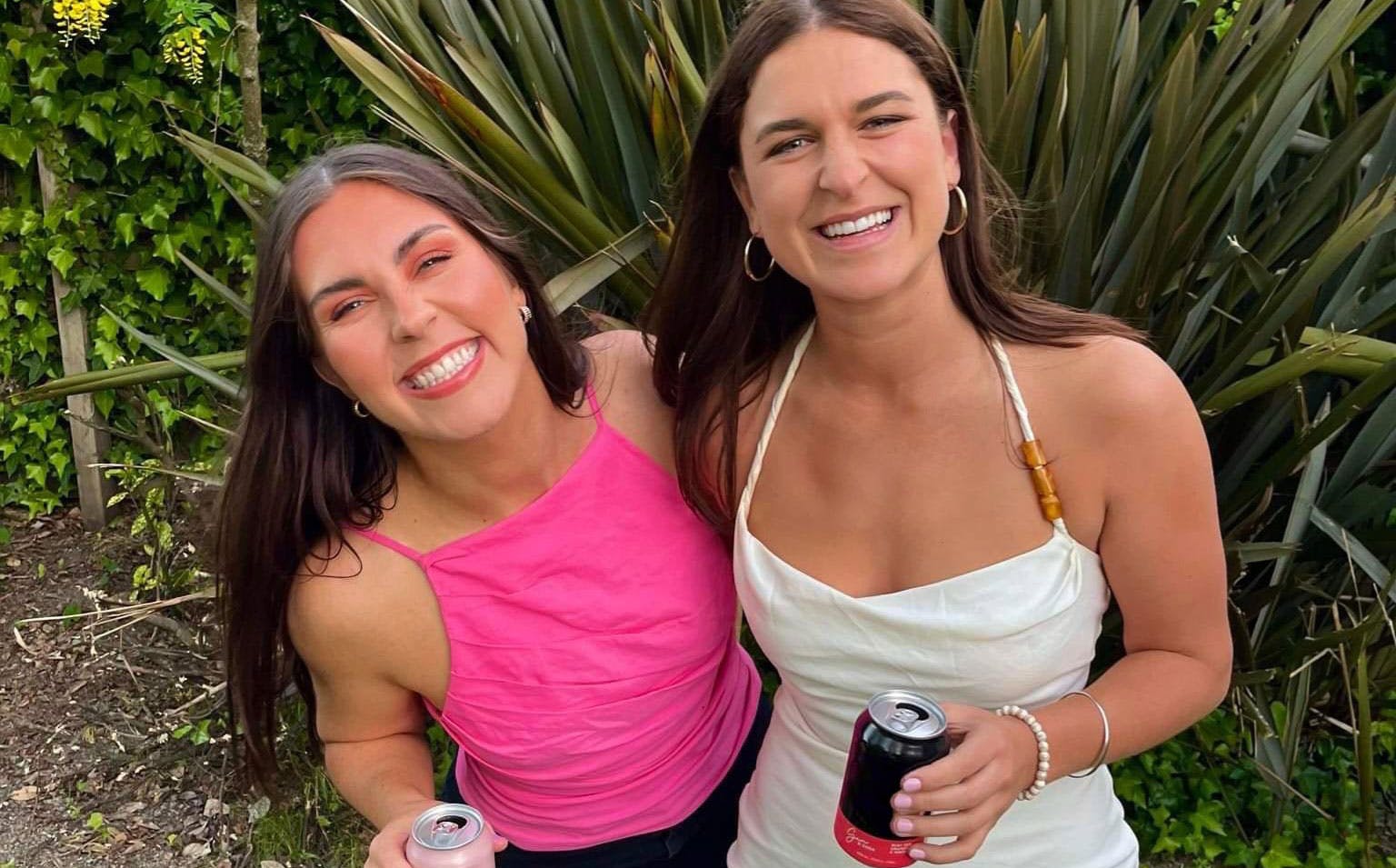 Two girls smile at the camera outdoors