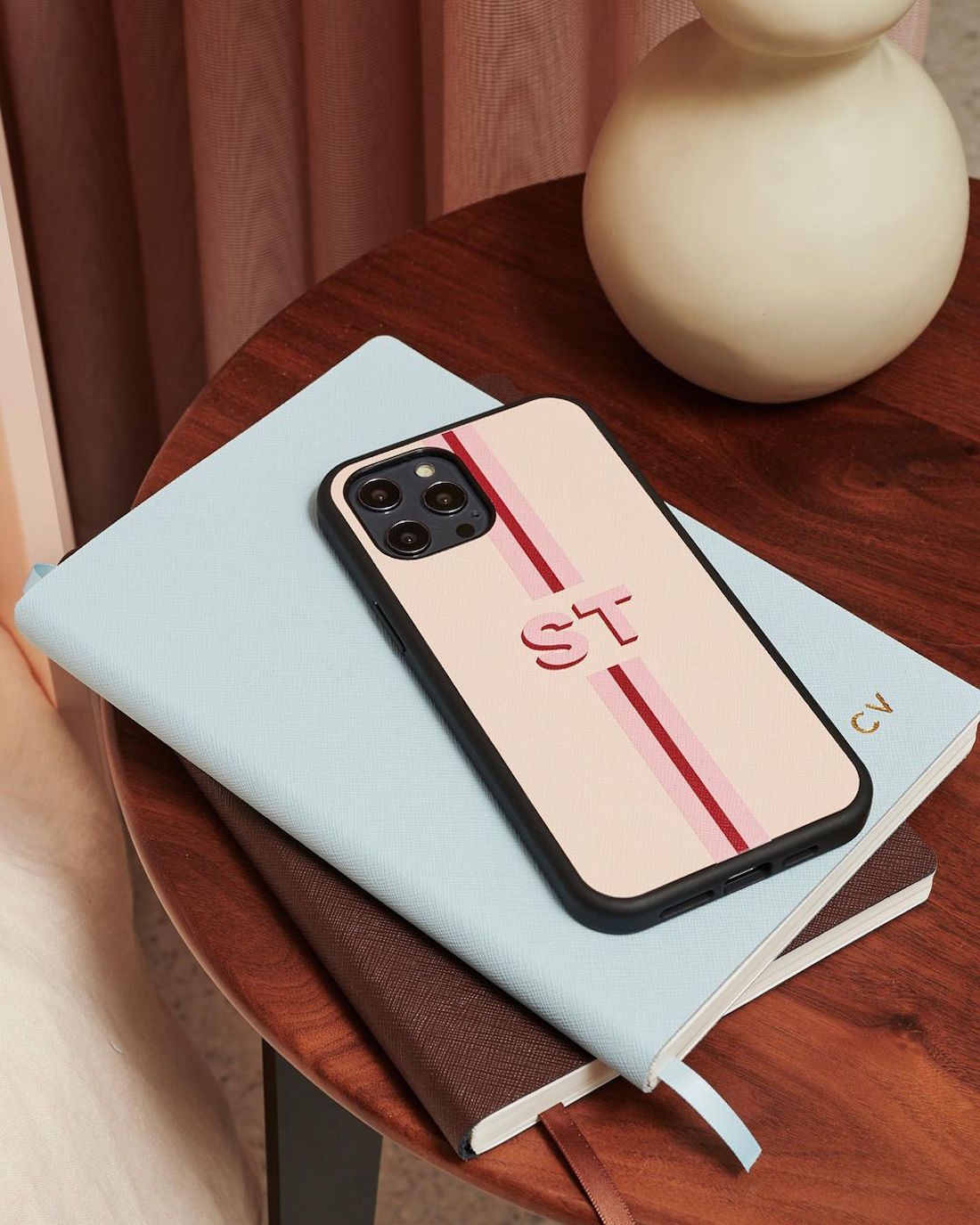 A monogrammed phone case rests atop a monogrammed notebook.