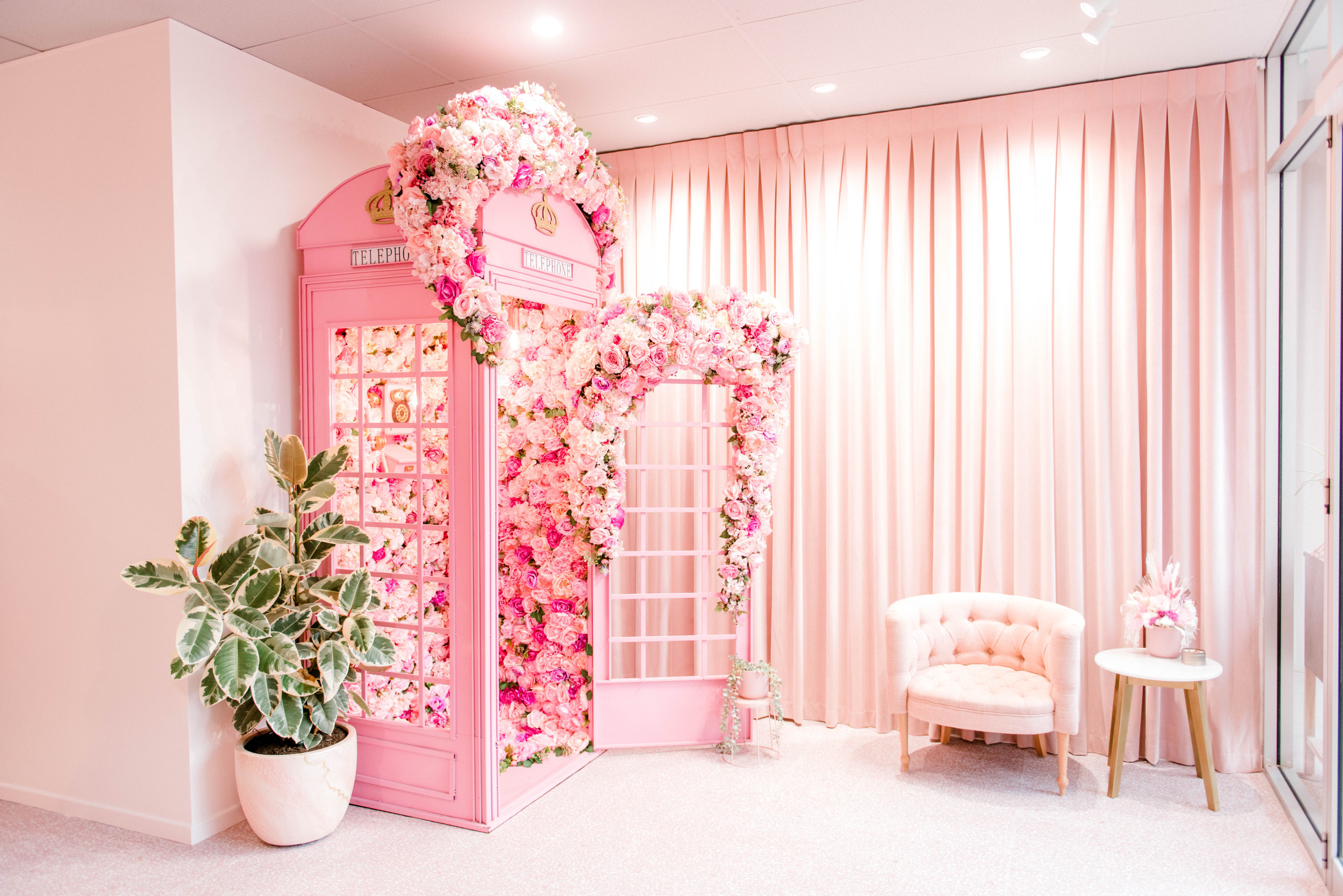 a beautiful pink phone booth covered in flowers