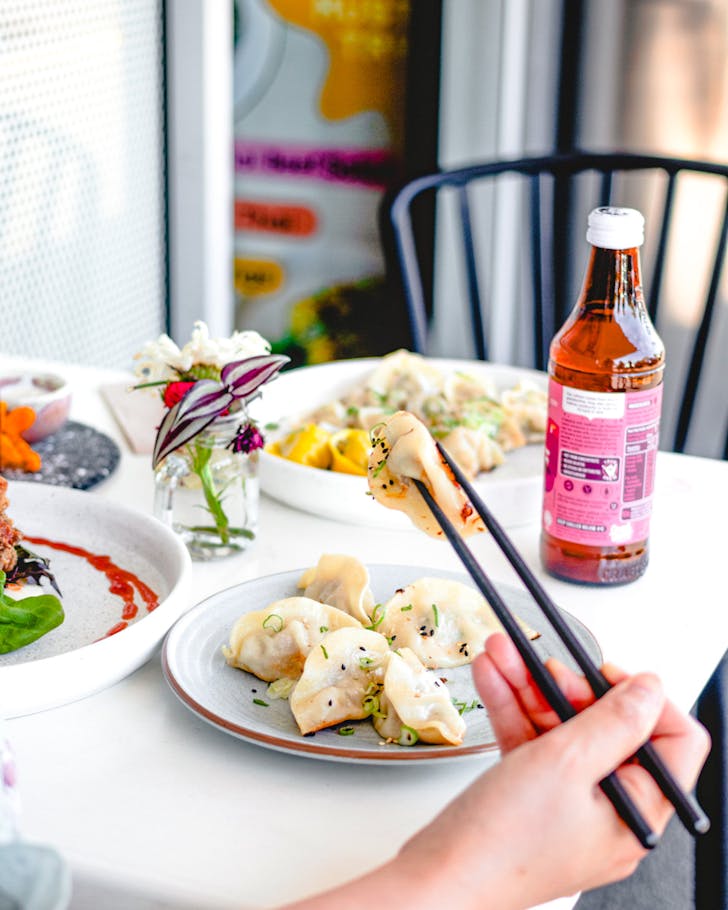 Someone picks up a juicy dumpling chopsticks at Table Of Munchies (TOM). 