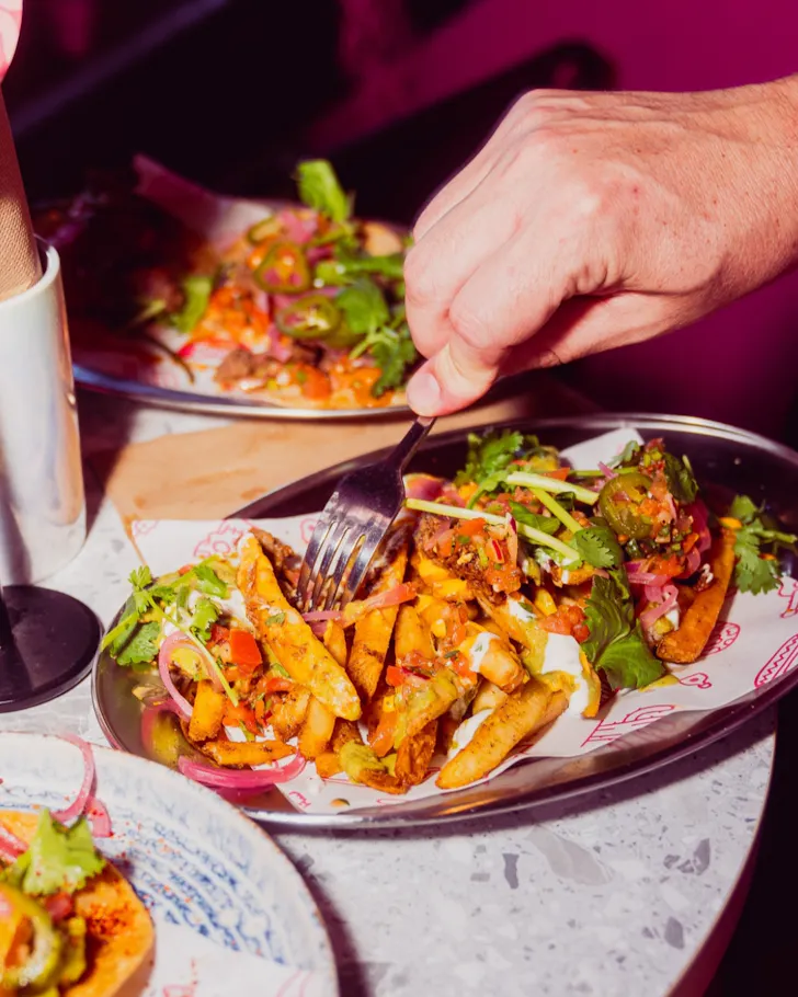 Hand seasoning plate of loaded nacho fries
