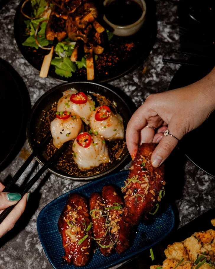 Hand grabbing dumpling from dark plate